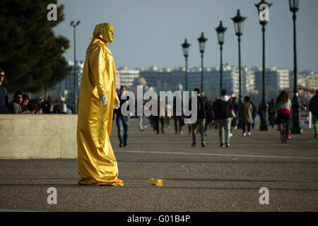 Eine Straße Straßenmusiker Pantomime trägt ein gold reflektierende Pailletten Kleid für Trinkgelder zu arbeiten auf neue Hafengebiet von Saloniki. Stockfoto