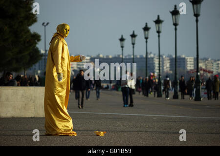 Eine Straße Pantomime trägt ein gold Pailletten Kleid, die live auf Thessalonikis Waterfront, in der Nähe von White Tower. Stockfoto