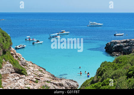 Menorca, Balearen: Boote und Touristen am Strand Menorcas. Die Insel hat eine Vielzahl von Stränden, überfüllt und nicht überfüllt Stockfoto