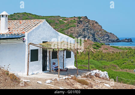 Menorca, Balearen, Spanien: ein Mann im Schatten liegen unter einer Veranda in der Cala Mesquida Stockfoto