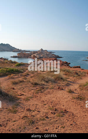 Menorca: Roter Sand auf dem Weg zur Cala Pregonda, einsamen Bucht mit Felsen, eine Landschaft wie der Planet Mars Stockfoto