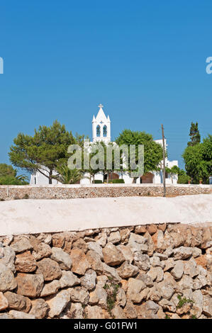 Menorca, Balearen, Spanien, Europa: eine Mauer aus Stein und eine weiße Kirche in der Landschaft Menorcas Stockfoto