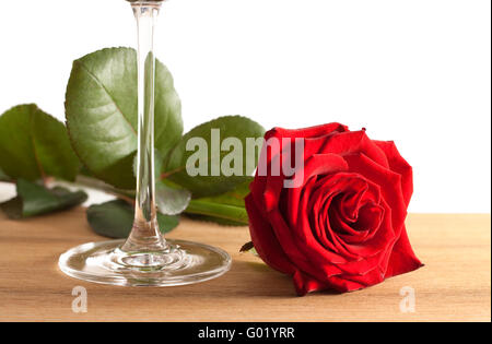 Eine rote Rose und ein Glas Wein auf einem hölzernen Boden isoliert auf weißem Hintergrund Stockfoto