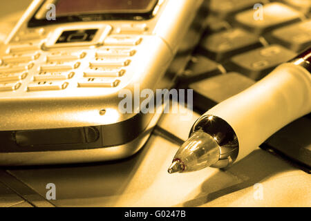 Stift und Handy auf Computer-Tastatur in orange Stockfoto