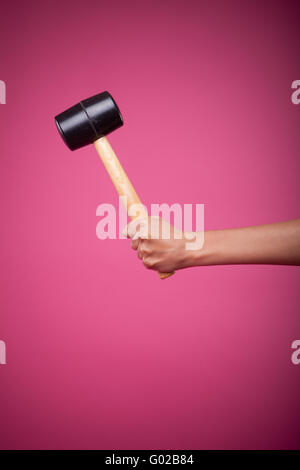 weibliche Hand mit Hammer auf rosa Hintergrund Stockfoto