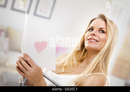 Frau liest ein Valentinstag-Karte im Wohnzimmer Stockfoto