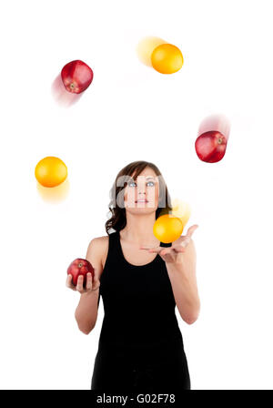 Schöne Frau Jonglage Äpfel und Orangen auf einem w Stockfoto