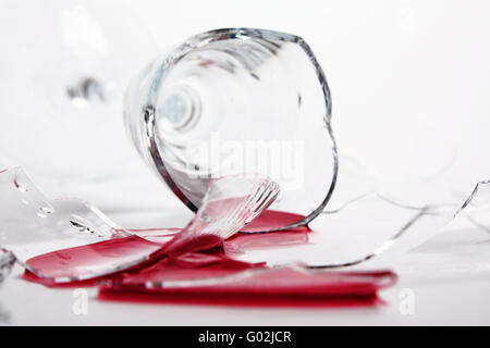 Zerbrochene Weinglas auf dem Tisch. Gegossene Rotwein Stockfoto