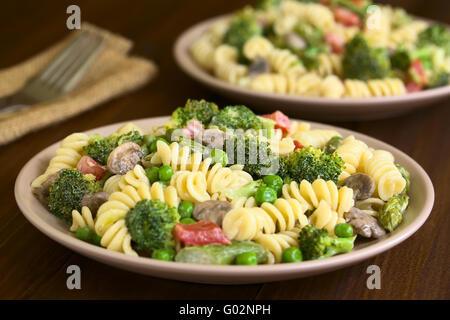 Pasta Primavera mit grünem Spargel, Erbsen, Brokkoli, Pilzen und Tomaten in Sahne-Sauce auf Tellern serviert Stockfoto