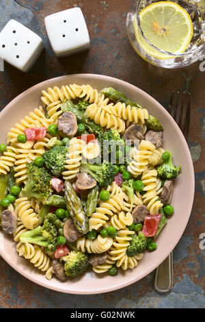 Pasta Primavera mit grünem Spargel, Erbsen, Brokkoli, Pilzen und Tomaten in Sahne-Sauce auf Teller serviert Stockfoto