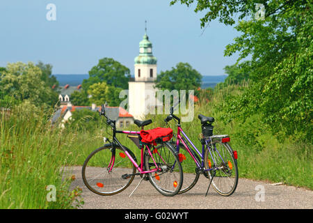 Zwei Fahrräder stehen auf der Straße mit einer Kirche im Hintergrund - Pause während der Radtour Stockfoto