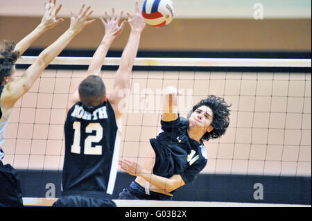 High School Spieler versucht, einen Volley mit einer Tötung Schuß über eine Sperrminorität Bemühen eines Gegners zu beenden. USA. Stockfoto