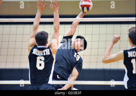 High School Spieler versucht, einen Volley mit einer Tötung Schuß über eine Sperrminorität Bemühen eines Gegners zu beenden. USA. Stockfoto