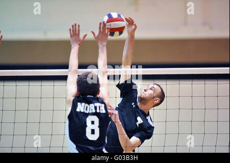 High School Spieler versucht, einen Volley mit einer Tötung Schuß über eine Sperrminorität Bemühen eines Gegners zu beenden. USA. Stockfoto