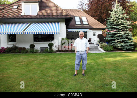 Freundlichen Senior vor seinem Haus im Garten Stockfoto