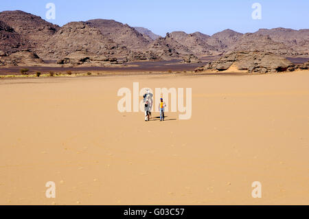 Zwei Touristen und ihr Kamel in der Sahara zu Fuß Stockfoto