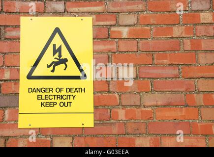 Hochspannung gelben Warnschild auf eine Wand Backsteingebäude Stockfoto