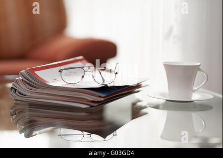 Stapel von Zeitungen, Gläser und Kaffeetasse auf einem g Stockfoto