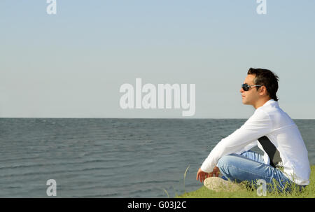 kaukasischen Jüngling saß allein und Blick zum Meer Stockfoto
