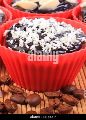 Hausgemachte leckere frisch gebackene Schokoladen Muffins mit Dehydriertes Coconut und geschnittene Mandeln rot Silikon Cups Stockfoto