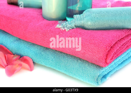 Rosa und blaue Handtücher mit Solt, Creme, Shampoo, Bodylotion, Schaumbad, Duschgel Stockfoto