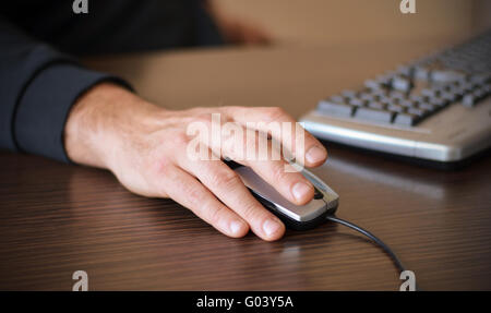 Hand eines Mannes, die Arbeit am Computer Maus auf dunklen Desktop anklicken Stockfoto