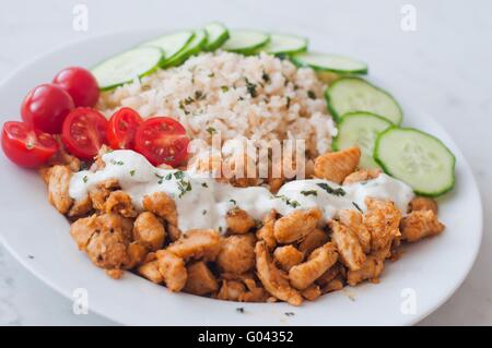 Gyros Hähnchen auf einem Teller mit Reis, Tzatziki Dressing und Gemüse - Tomate, Gurke Stockfoto