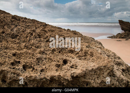 Felsen am Sandstrand im Vordergrund. Windigen Herbsttag mit vielen Wolken. Gewässern des Atlantischen Ozean im Hintergrund. Moula Stockfoto