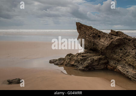 Felsen am Sandstrand im Vordergrund. Windigen Herbsttag mit vielen Wolken. Gewässern des Atlantischen Ozean im Hintergrund. Moula Stockfoto