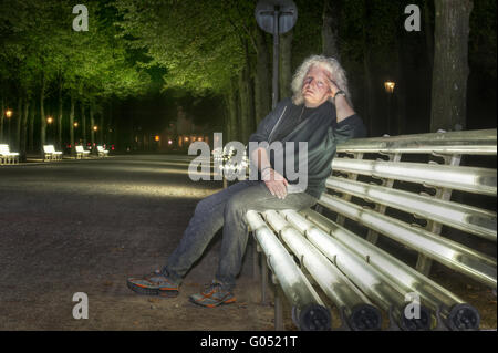 ein Mann sitzt auf einer Bank in den Innenhof Garten ligh Stockfoto