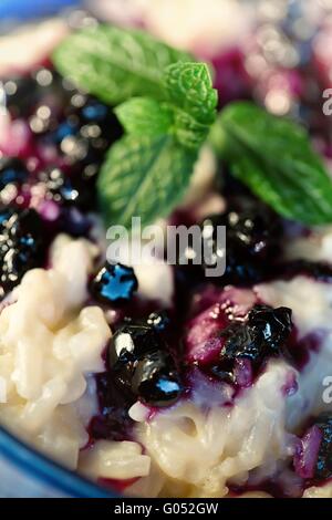 Milchreis mit Heidelbeeren in die blaue Schale (selektiven Fokus Stockfoto