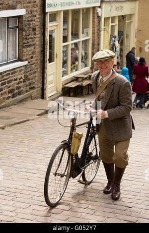 Großbritannien, England, Yorkshire, Haworth 40er Jahre Wochenende, Main Street, Adrian Worral, aus St. Annes schob sein Rad den Berg hinauf. Stockfoto