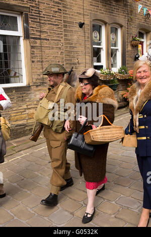 Großbritannien, England, Yorkshire, Haworth 40er Jahre Wochenende, Main Street, paar in Kriegszeiten Kostüm zu Fuß bergab Stockfoto