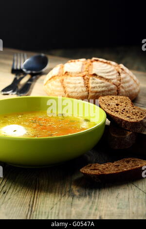 Pochiertes Ei mit Hühnerbrühe in eine grüne Platte. Stockfoto