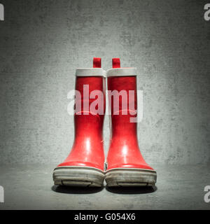 Rote Gummistiefel vor Steinmauer. Stillleben mit verwendet wasserdicht Lackoptik. Stockfoto