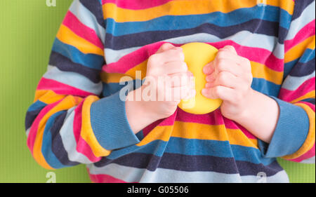 Kind hält und gelbe Stress-Ball mit Händen zu quetschen. Konzept der Kindheit Angst, Frustration und Wut. Auch ein Symbol der Stockfoto