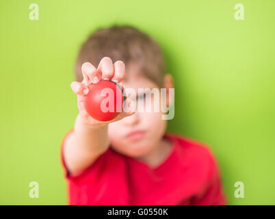 Kind hält und rote Stress-Ball mit der Hand zusammendrücken. Konzept der Kindheit Angst, Frustration und Wut. Auch ein Symbol der bei Stockfoto