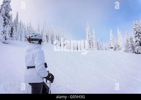 Frau genießen den Blick auf die Skipisten von Sun Peaks Skigebiet umgeben von tief verschneiten Bäumen in den hohen Alpen Stockfoto