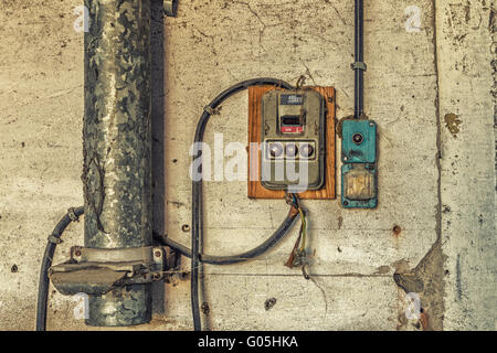 Elektrotechnische Industrie Archäologie - altes elektrisches Licht alt und elektrische Schalttafel mit Ventilen und Sicherungen entlang Metallrohr Stockfoto