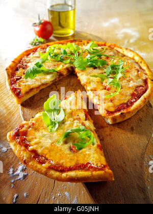 Gekochte ganze Käse und Tomaten Pizza Margherita mit Rucola und eine geschnittene Scheibe Stockfoto