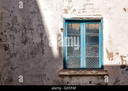 An der Grenze zwischen Licht und Schatten blau gerahmte Fenster, das Sonnenlicht reflektiert. Stockfoto