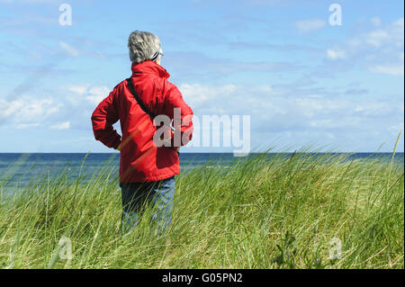 eine Frau steht in den Dünen und befasst sich mit der Stockfoto