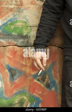 Die Hand des Mannes mit einer Zigarette auf der Graffitiwand Stockfoto