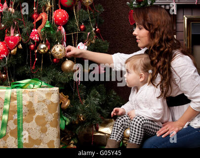 Glückliche Mutter dekorieren Weihnachtsbaum mit ihrem baby Stockfoto