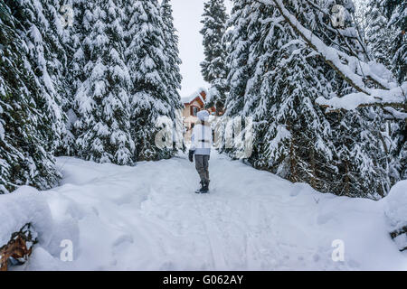 Ältere Frau zu Fuß durch eine tiefe Schneedecke in Sun Peaks Village in der Shuswap-Hochland von britischen Columba, Kanada Stockfoto