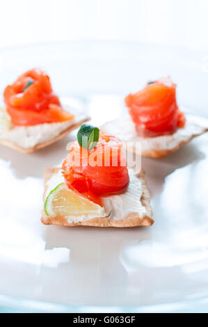 Kanapees mit Lachs Käse-Kalk und Rosmarin auf weißen Teller Stockfoto