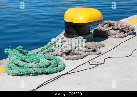 Gelbe Festmacher Poller und nautischen Seile sind am Pier im Frachthafen Stockfoto