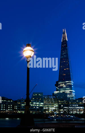 Nacht-Blick auf die Skyline von London zeigt The Shard und eine Straßenlaterne Stockfoto