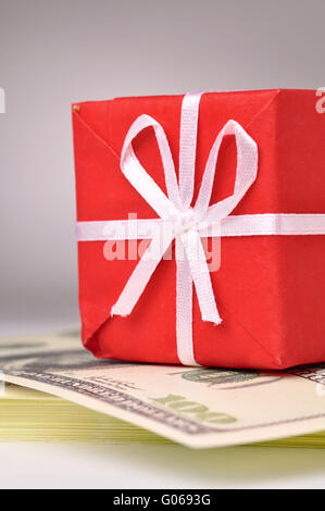 roten Geschenk-Box auf der Bacth der Dollar-Noten Stockfoto