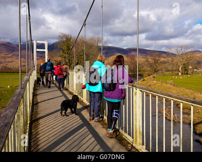 Hund Wanderer bewundern die Landschaft von einer Fußgängerbrücke über den Fluss Derwent in Keswick Lake District National Park Cumbria England UK Stockfoto